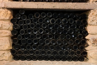 Many wine bottles on shelf in cellar