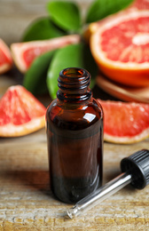 Citrus essential oil and grapefruits on wooden table