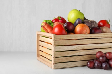 Wooden crate full of different vegetables and fruits on light table. Harvesting time
