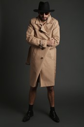 Photo of Exhibitionist in coat and hat on black background