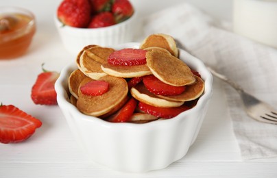 Delicious mini pancakes cereal with strawberries served on white wooden table