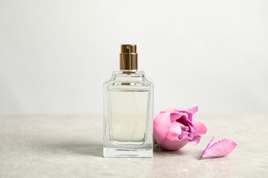 Bottle of perfume and beautiful rose on light table