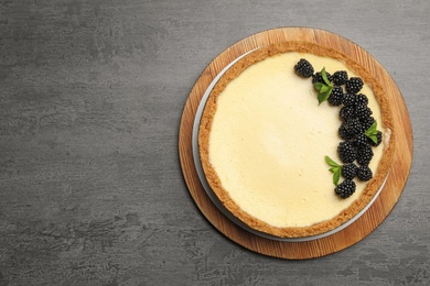 Delicious cheesecake decorated with blackberries on grey table, top view. Space for text