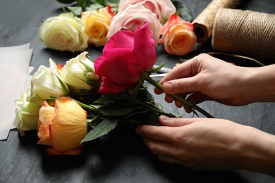 Woman making luxury bouquet of fresh roses at black table, closeup