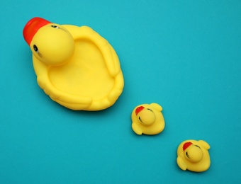 Rubber toy ducks on teal background, flat lay