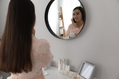 Young woman applying face cream at home. Morning routine
