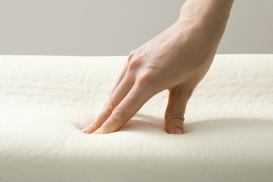 Photo of Woman touching orthopedic memory foam pillow, closeup