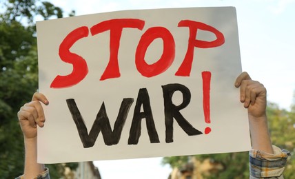 Woman holding poster with words Stop War outdoors, closeup