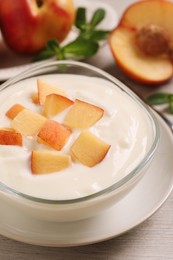 Delicious yogurt with fresh peach on light wooden table, closeup