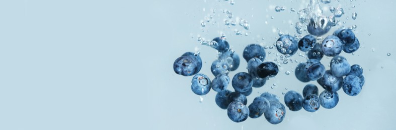 Fresh ripe blueberries falling in water on grey background, space for text. Banner design