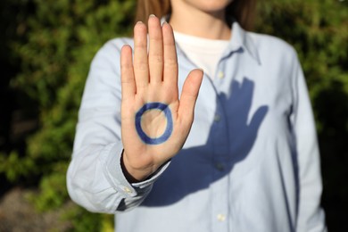 Photo of Woman showing blue circle drawn on palm outdoors, closeup. World Diabetes Day