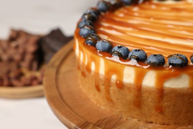 Delicious cheesecake with caramel and blueberries, closeup. Space for text