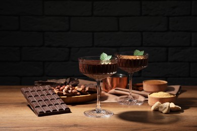 Photo of Dessert bowls of delicious hot chocolate and ingredients on wooden table