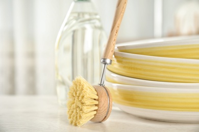 Cleaning brush for dish washing near bowls on white table indoors, closeup
