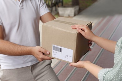 Woman receiving parcel from courier outdoors, closeup