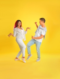 Beautiful lovely couple dancing on yellow background