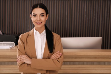 Portrait of receptionist near countertop in office, space for text