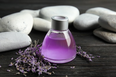 Natural herbal oil and lavender flowers on wooden background