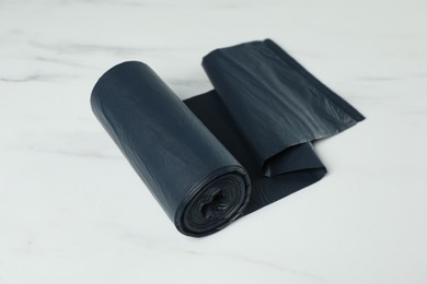 Photo of Roll of black garbage bags on white marble table