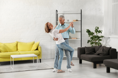 Happy senior couple dancing in living room