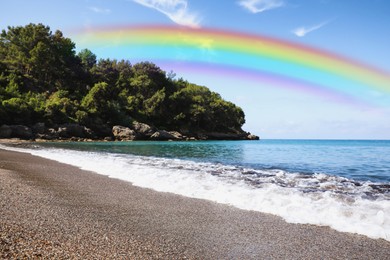 Beautiful rainbow in blue sky over beach and sea on sunny day