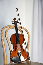 Classic violin and bow on chair near light wall