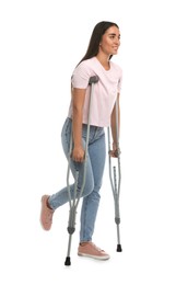 Young woman with axillary crutches on white background