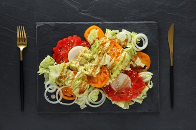 Delicious salad with Chinese cabbage, tomatoes and onion served on black table, flat lay