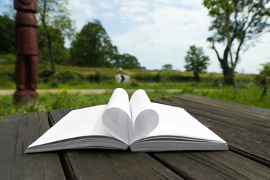 Photo of Open book on wooden table in countryside
