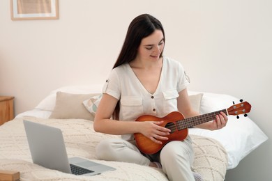 Photo of Woman learning to play ukulele with online music course at home. Time for hobby
