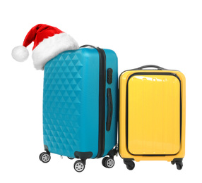Stylish suitcases with Santa Claus hat on white background. Christmas vacation 