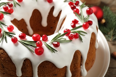 Traditional Christmas cake decorated with glaze, pomegranate seeds, cranberries and rosemary, closeup