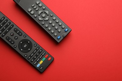 Remote controls on red background, flat lay. Space for text