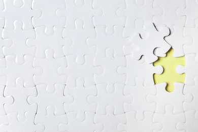 Blank white puzzle with separated piece on yellow background, top view. Space for text