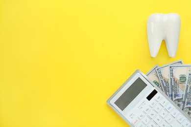 Ceramic model of tooth, dollar banknotes and calculator on yellow background, flat lay with space for text. Expensive treatment