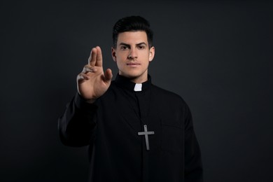 Priest making blessing gesture on black background