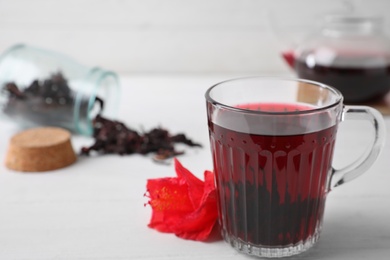 Delicious hibiscus tea and flower on white wooden table. Space for text