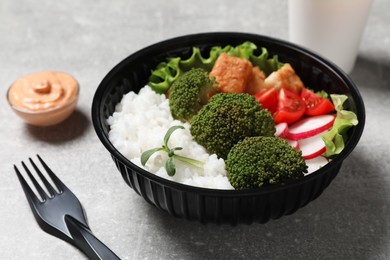 Healthy takeaway meal in plastic bowl on light grey table