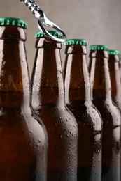 Opening bottle of beer on light brown background, closeup