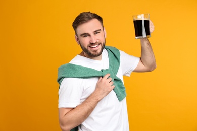 Handsome man with cold kvass on yellow background. Traditional Russian summer drink