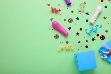 Flat lay composition with colorful confetti and box on light green background, space for text