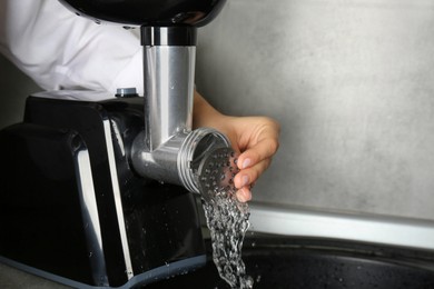 Photo of Woman washing electric meat grinder indoors, closeup. Space for text