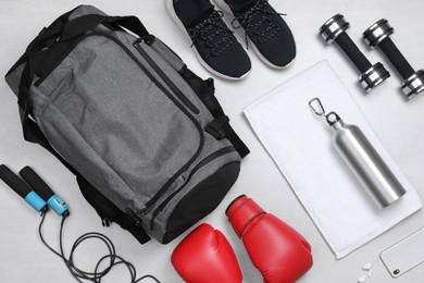 Gym bag and sports equipment on white background, flat lay