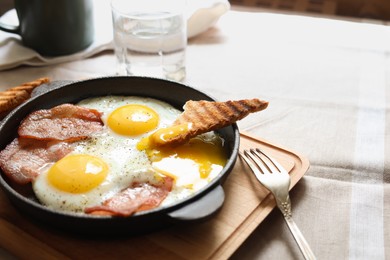 Tasty fried eggs with bacon and toast on table, closeup. Space for text