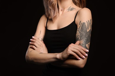 Beautiful woman with tattoos on body against black background, closeup