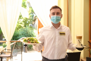 Waiter serving salad and coffee in restaurant. Catering during coronavirus quarantine