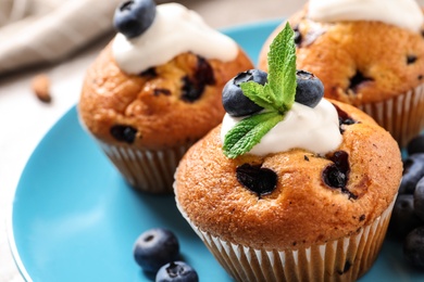 Photo of Plate of tasty muffins and blueberries on table, closeup