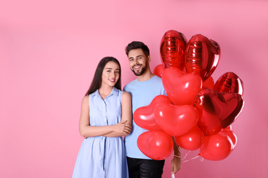 Lovely couple with heart shaped balloons on pink background. Valentine's day celebration