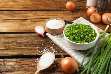 Chopped green onion in bowl on wooden table, space for text