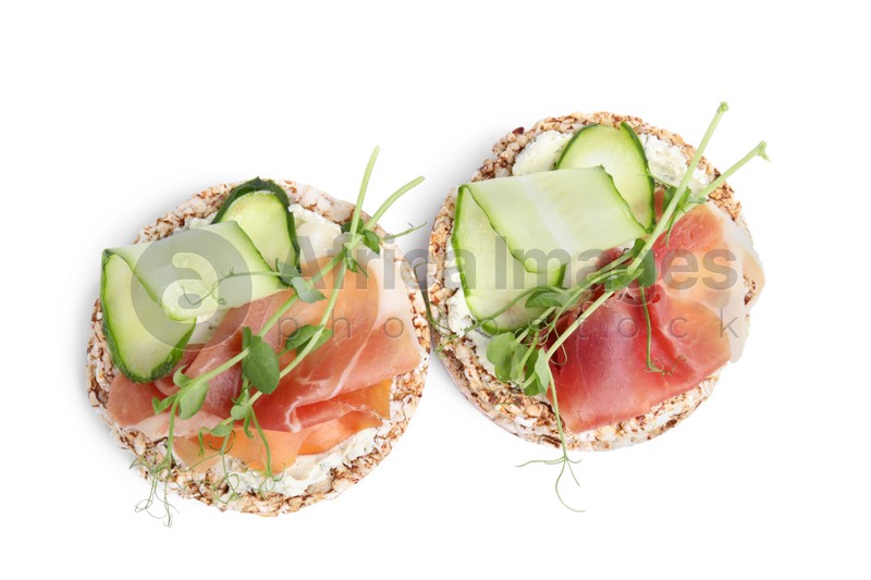 Crunchy buckwheat cakes with cream cheese, prosciutto and cucumber slices on white background, top view